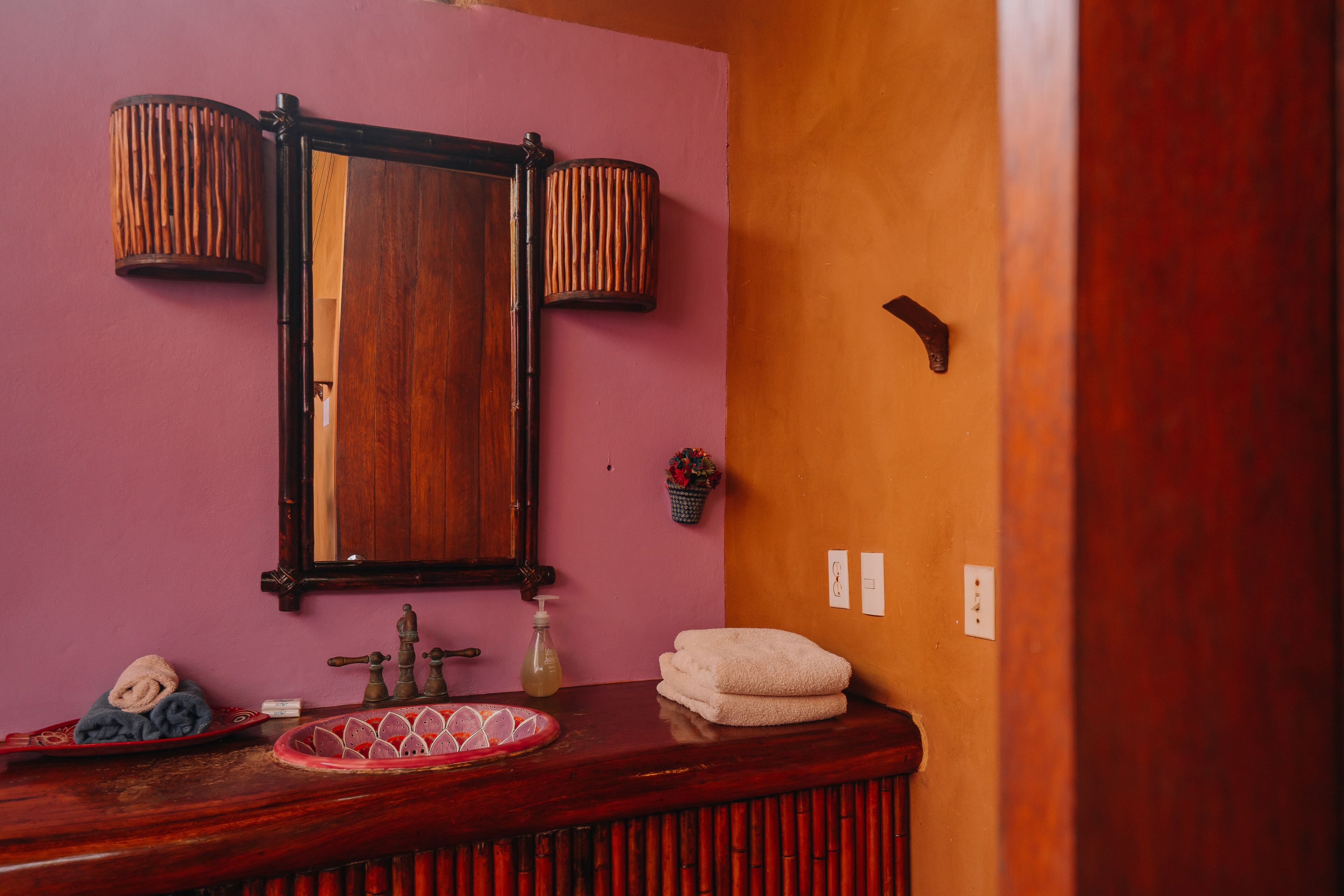 A bathroom with a wooden vanity, a mirror, a sink, and a towel rack.