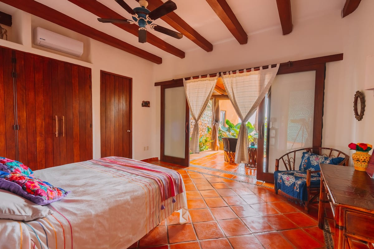 A bedroom with a bed, wooden wardrobe, and a ceiling fan.