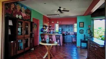 A spacious kitchen with a dining area, a ceiling fan, and a tiled floor.