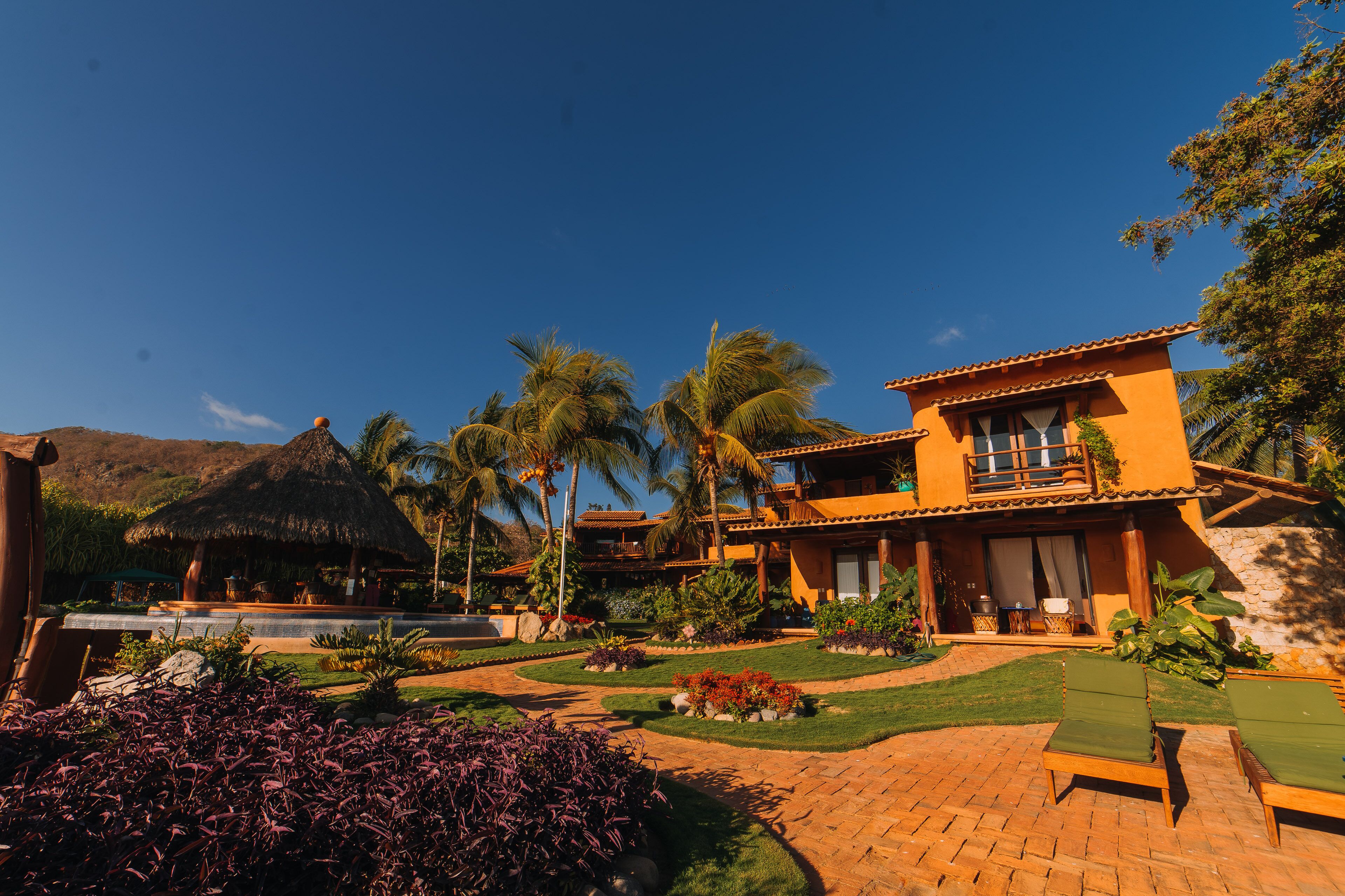 A resort with a pool, lounge chairs, and a well-maintained garden.