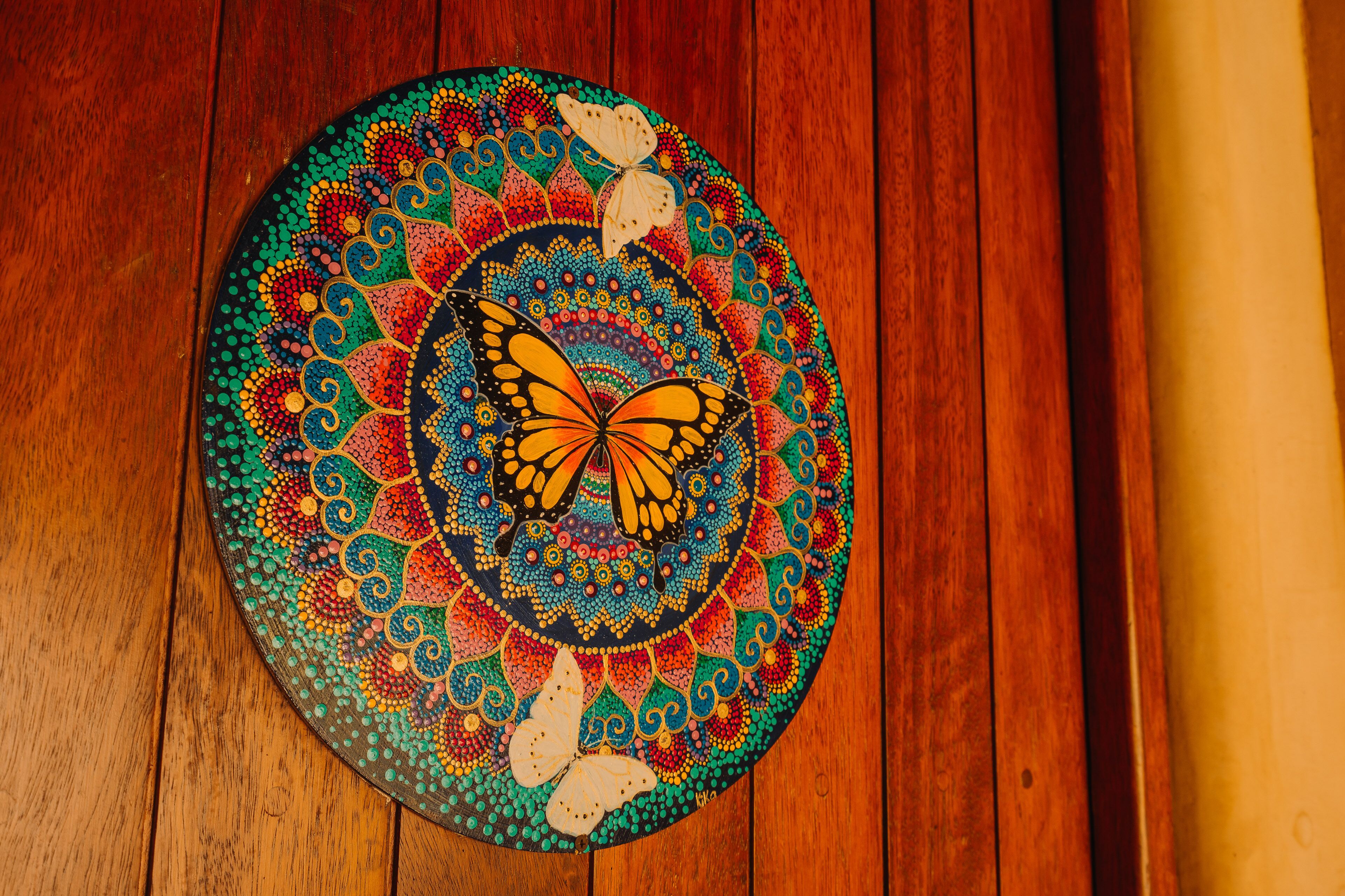 A circular, colorful artwork with a butterfly design on a wooden surface.