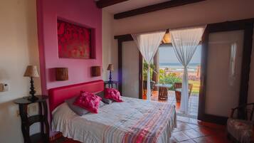 Une chambre avec un grand lit, un mur rose et une vue sur l’océan.