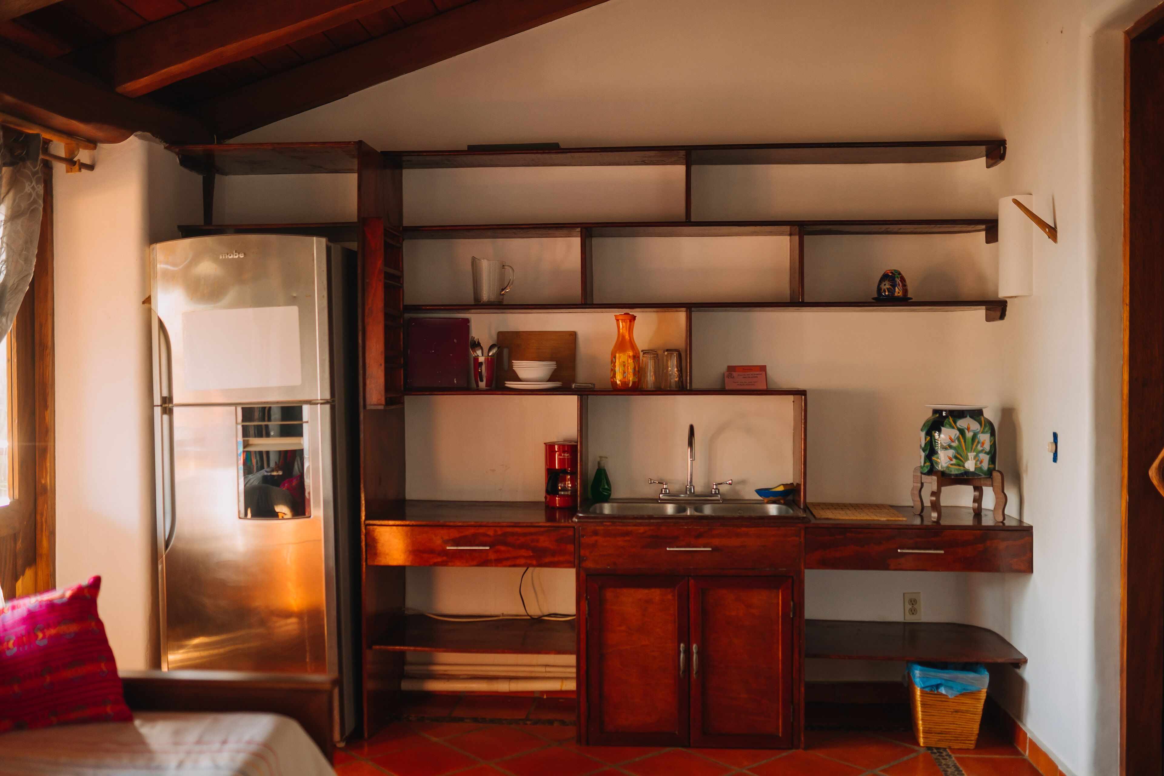 Una cocina compacta con refrigerador, armarios de madera y una encimera.