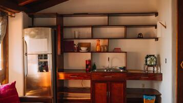 Una cocina compacta con refrigerador, armarios de madera y una encimera.