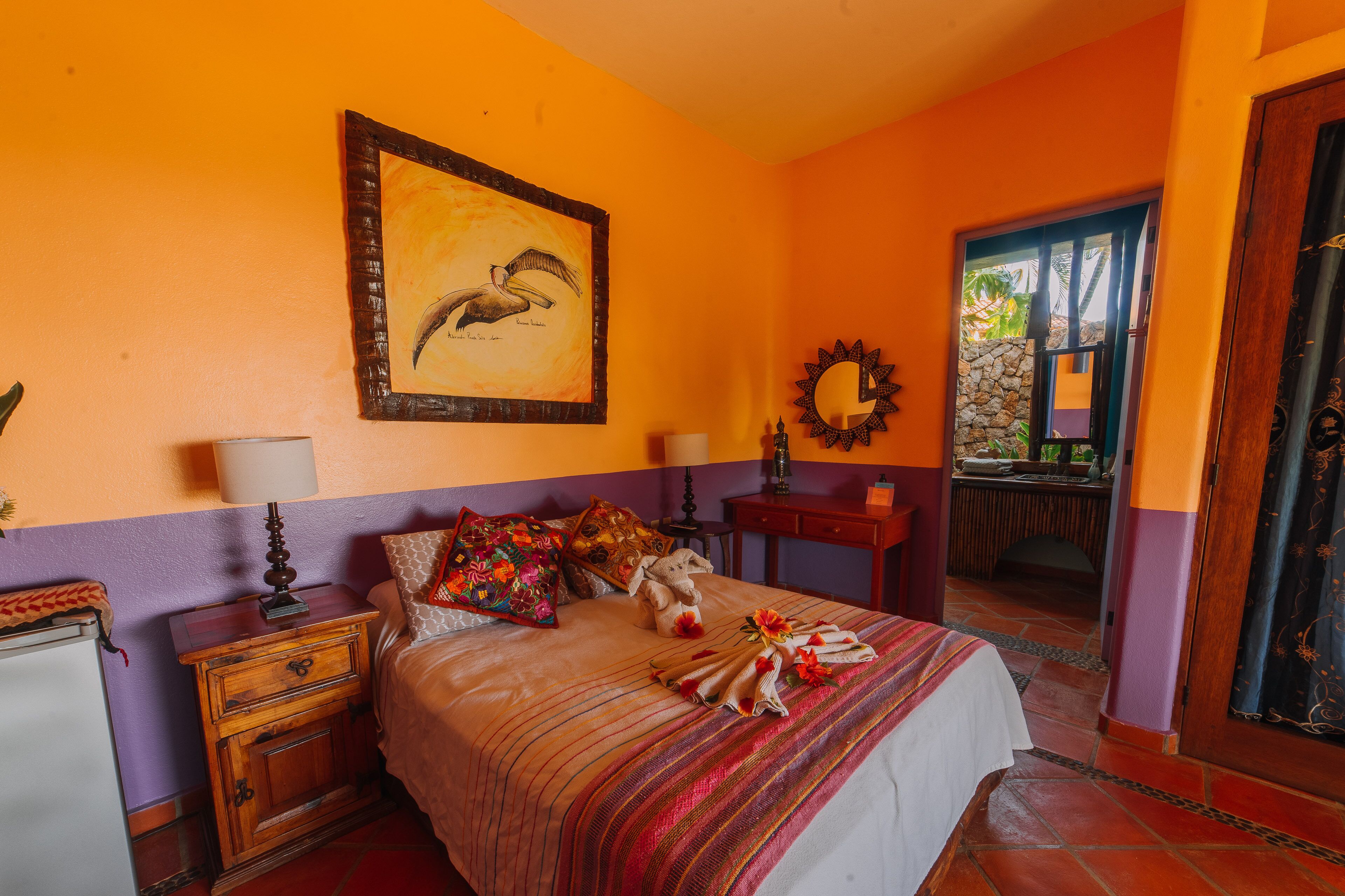 Un dormitorio con cama, mesita de noche, cómoda, espejo y puerta que da a un balcón.