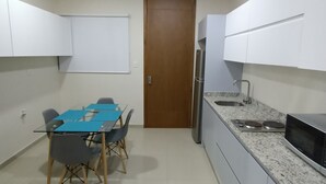 A compact kitchen with a dining area, white cabinets, a wooden door, and a stainless steel refrigerator. - beautiful loft ,two blocks from the beach , walk or ride a bike and explore  mzt (Mazatlán)