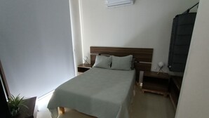 A bedroom with a bed, bedside tables, a nightstand, a wall-mounted air conditioner, and a potted plant. - beautiful loft ,two blocks from the beach , walk or ride a bike and explore  mzt (Mazatlán)