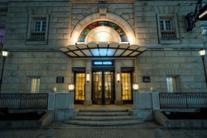 L’entrée de l’hôtel Koko, avec sa façade en pierre, ses fenêtres en arc de cercle et une enseigne au-dessus des portes.