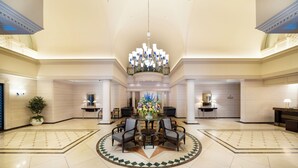 Eine geräumige Lobby mit einem runden Tisch in der Mitte, Sitzgelegenheiten und einem Kronleuchter.