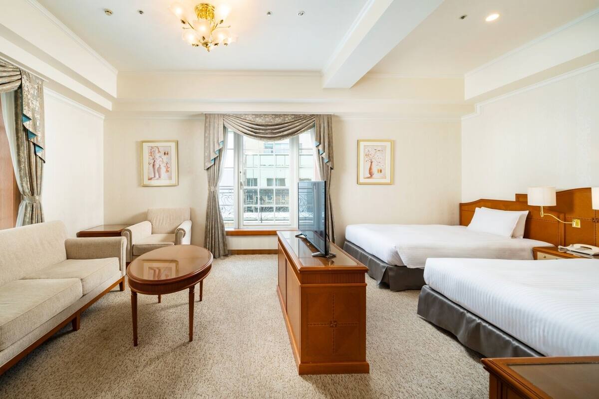 Une chambre d’hôtel comprenant un canapé, deux fauteuils, une table basse, un téléviseur, un lit et un bureau.