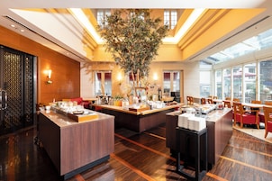 Un hall d’hôtel doté d’un comptoir d’accueil central, de coins salon et d’une grande plante d’intérieur.