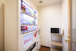 Máquina expendedora con varias bebidas y un microondas en un estante.