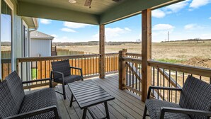 A covered outdoor deck with wicker furniture and a ceiling fan. - New Home in west Manhattan,  Family Friendly and close to KSU! (Manhattan)