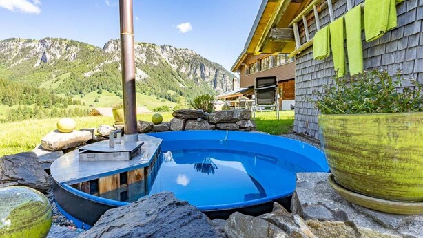 A hot tub surrounded by rocks and potted plants, with a mountain view in the background. - Berg Herz Grimmialp (Schwenden) by Interhome (Schwenden)