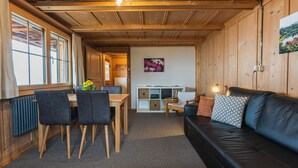 A cozy cabin interior with a dining area, a sofa, and a painting on the wall. - Berg Herz Grimmialp (Schwenden) by Interhome (Schwenden)