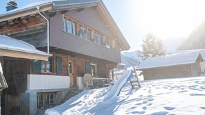 A wooden cabin with a snow-covered roof and a wooden deck. - Berg Herz Grimmialp (Schwenden) by Interhome (Schwenden)
