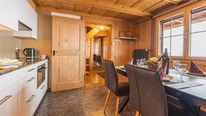 A wooden interior with a kitchen area, dining table, and chairs. - Berg Herz Grimmialp (Schwenden) by Interhome (Schwenden)
