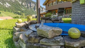 A modern house with a stone patio, a hot tub, and a view of mountains. - Berg Herz Grimmialp (Schwenden) by Interhome (Schwenden)