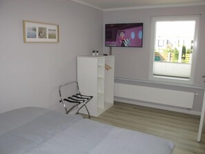 A bedroom with a bed, a white wardrobe, a TV mounted on the wall, and a window with a view of the outside. - Philipp by Interhome (Loissin)