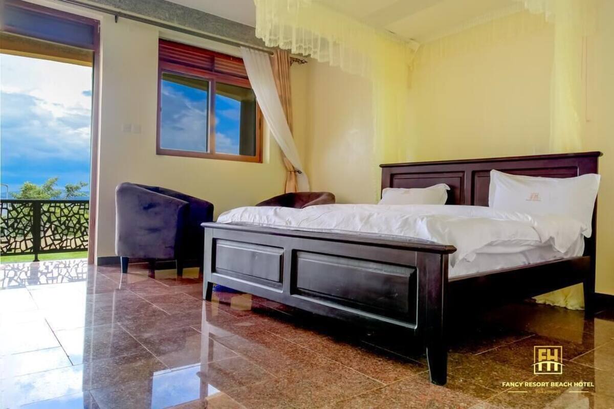 A bedroom with a large bed, a chair, and a view of the outside.