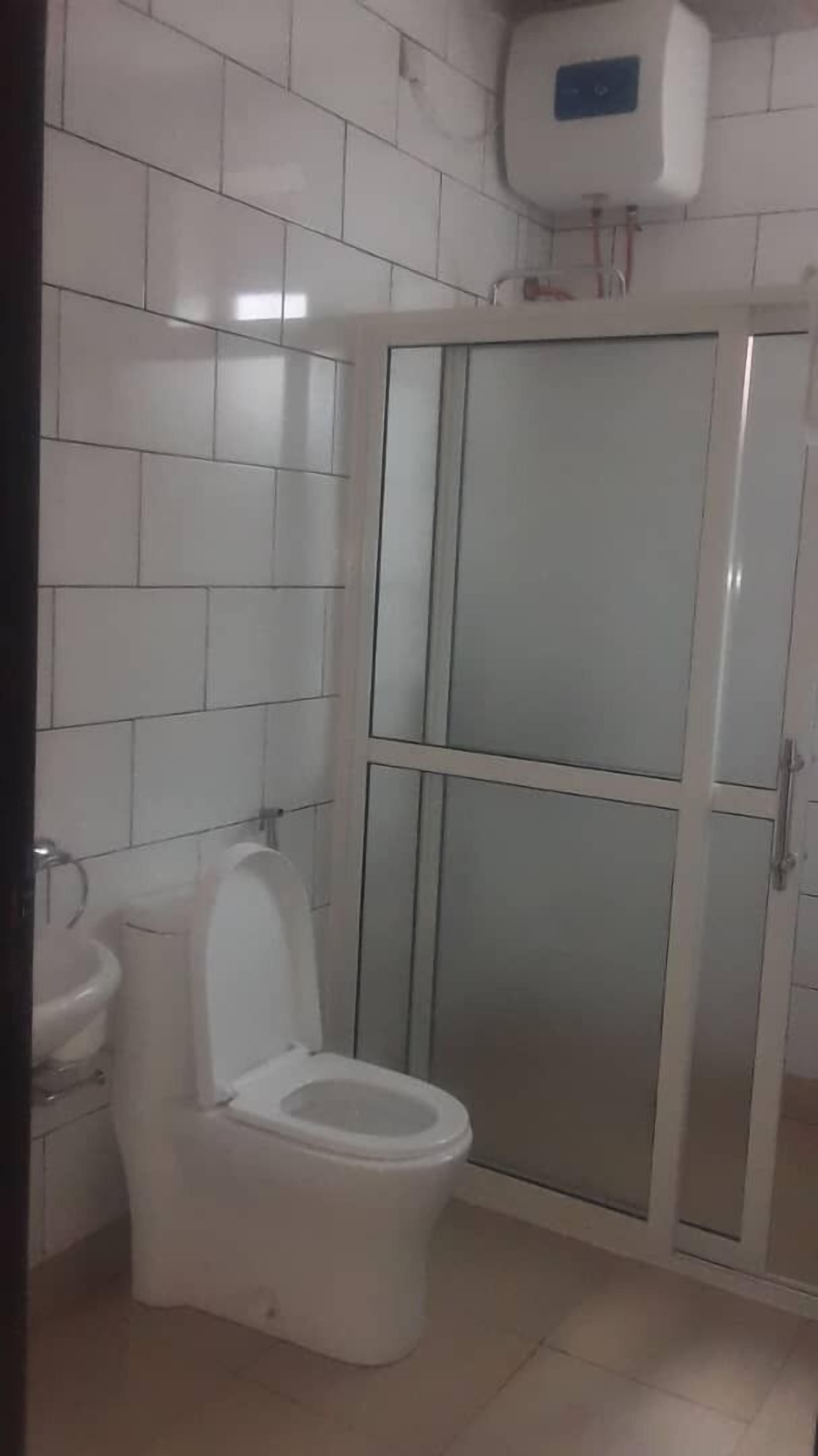A bathroom with a toilet, sink, and a glass-enclosed shower stall.