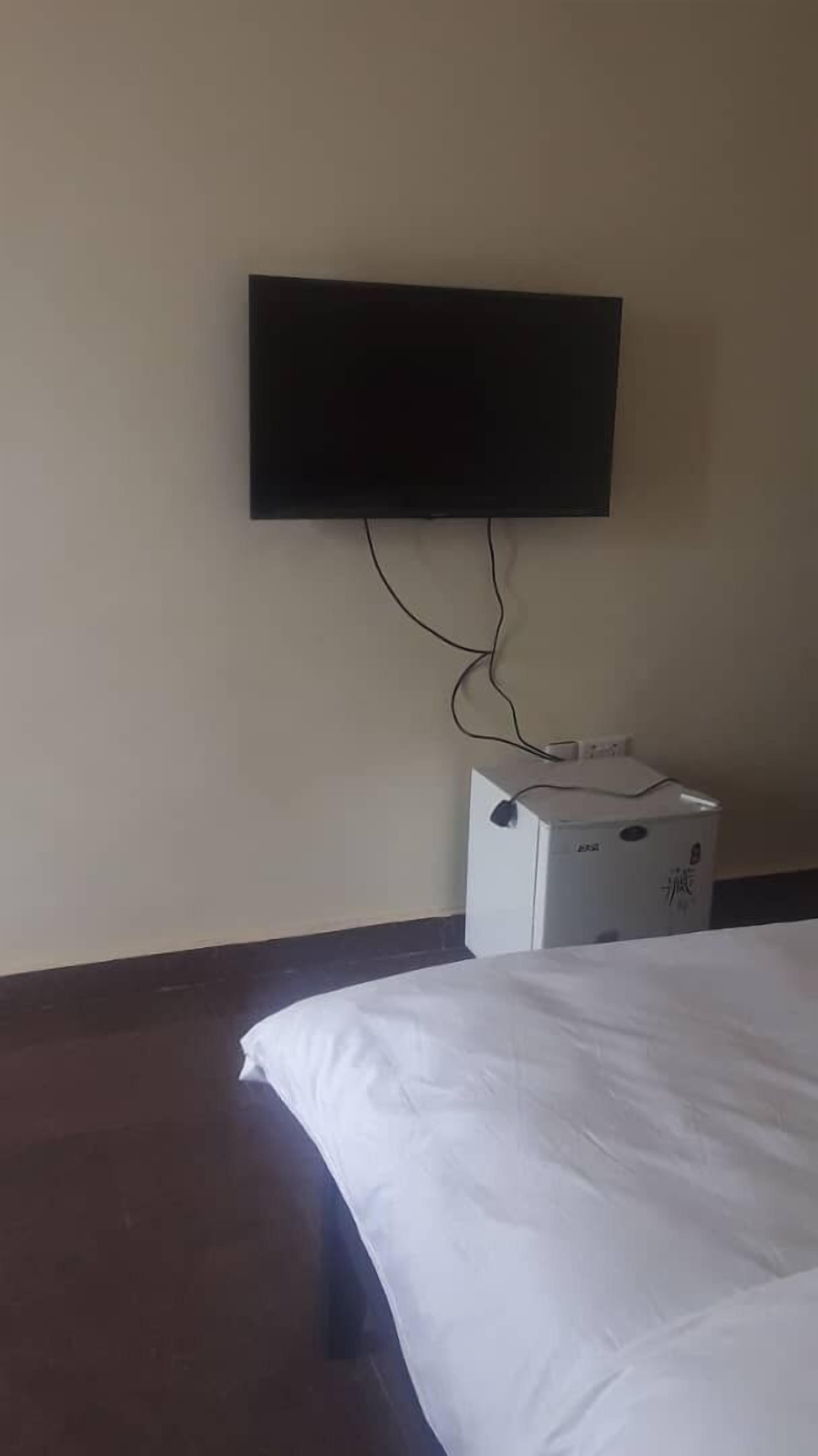 Hotelkamer met een bed, een flatscreen televisie aan de muur en een witte doos met Chinese karakters.