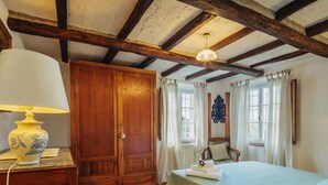 Ein Zimmer mit Holzschrank, Bett mit grüner Bettdecke, Lampe und einem fenster mit Vorhängen.