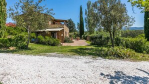 A rustic stone house with a gravel driveway, surrounded by lush greenery and tall trees. - Libeccio by Interhome (Marina di Bibbona)