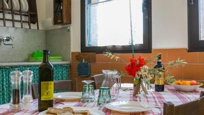 A dining table set with plates, a bottle, and a vase with flowers. - Libeccio by Interhome (Marina di Bibbona)