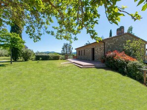 A stone house with a paved patio and a well-maintained lawn.