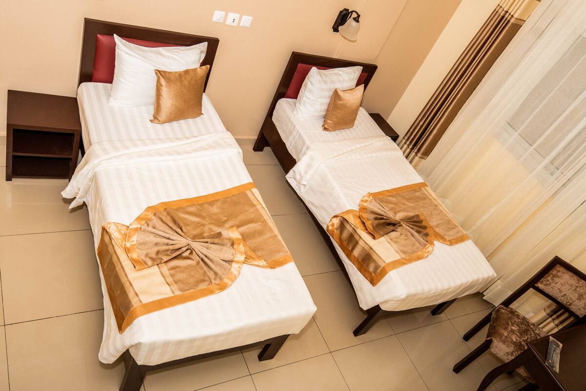 Two twin beds with matching headboards and footboards, a small bedside table, and a chair with a cushioned seat.