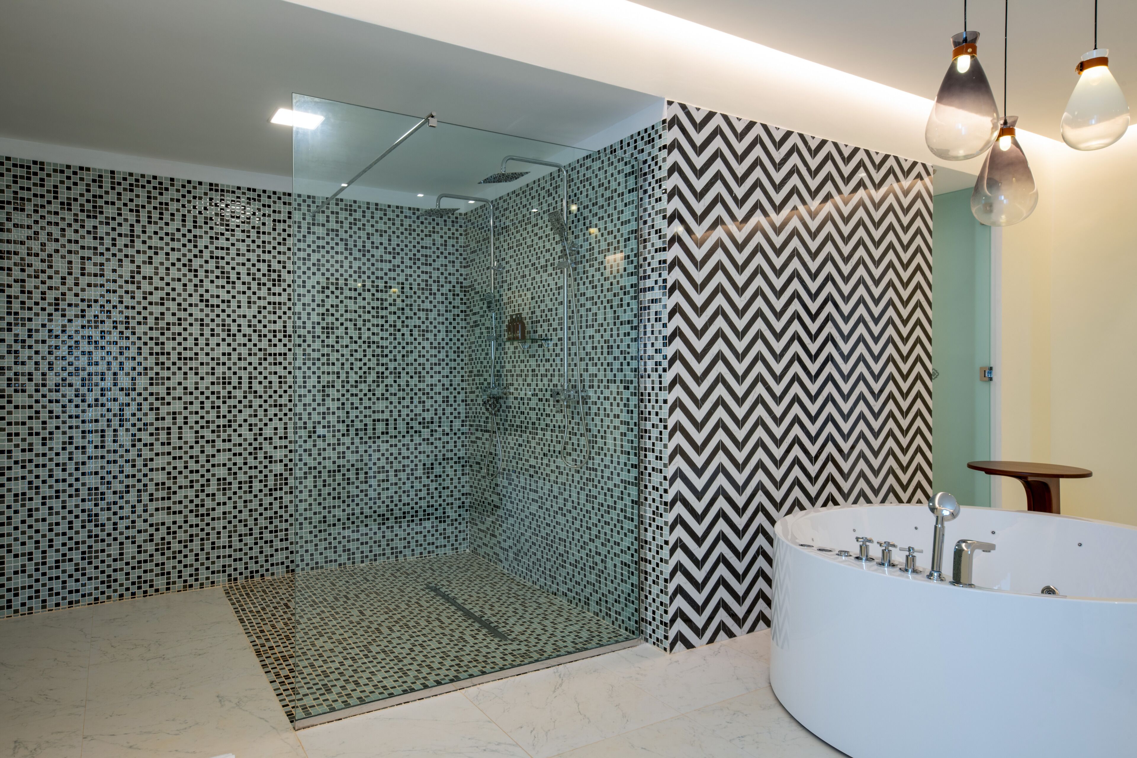Une salle de bain moderne avec une douche à parois de verre, une baignoire blanche et un miroir.