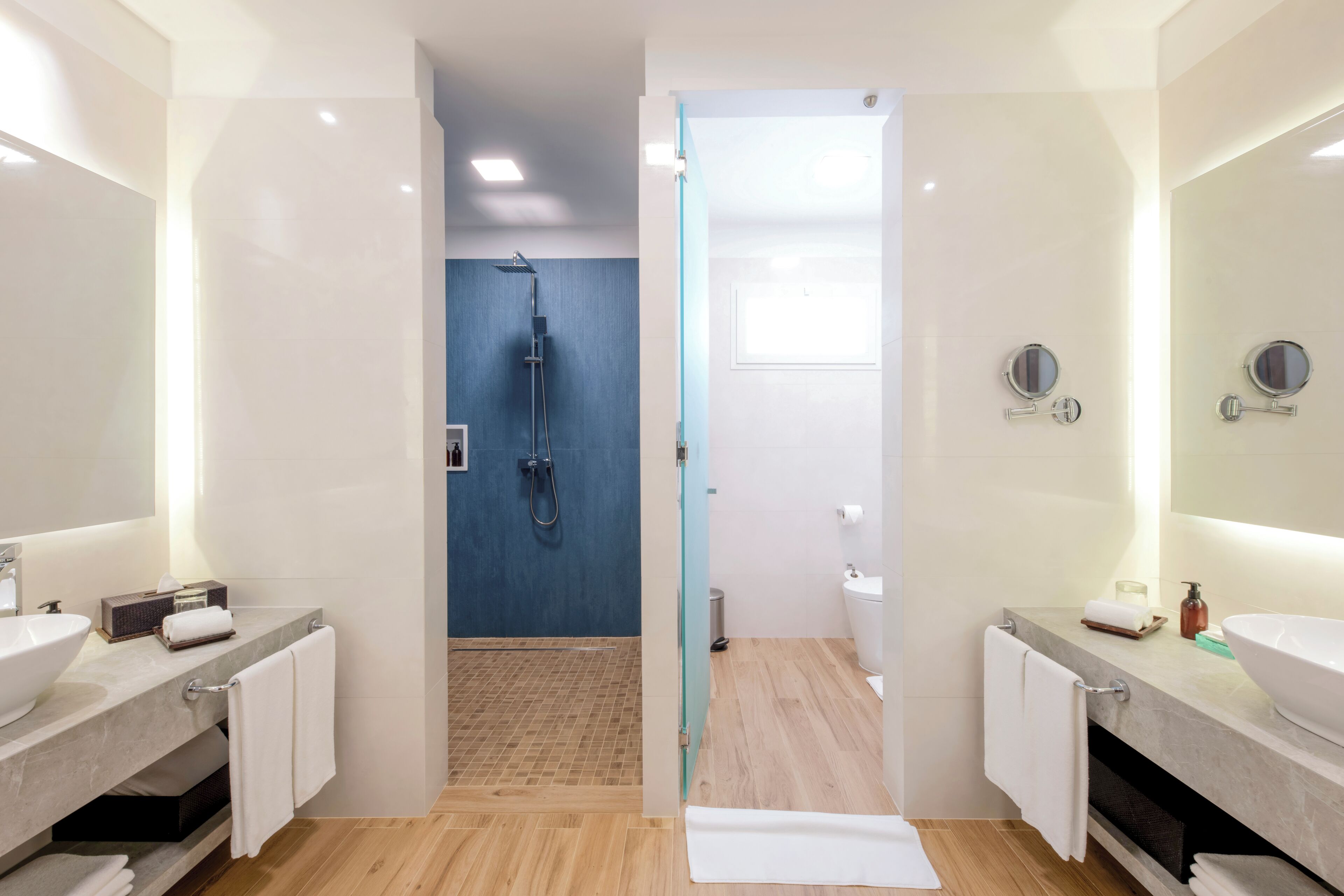 Een moderne badkamer met twee wasbakken, een douche en een spiegel.