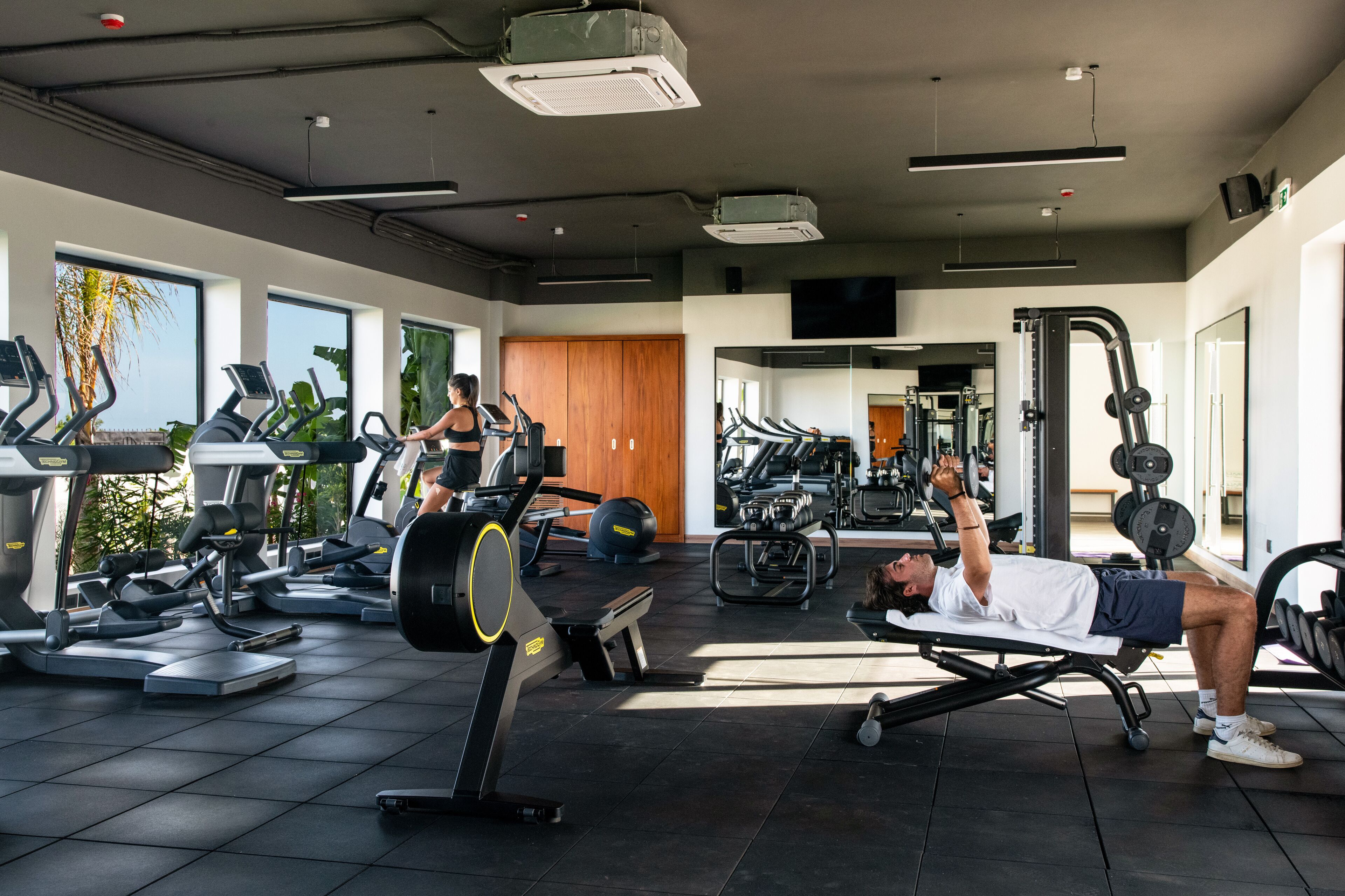 Une salle de sport équipée de tapis de course, d’appareils de musculation et d’une zone dédiée aux exercices de développé couché.