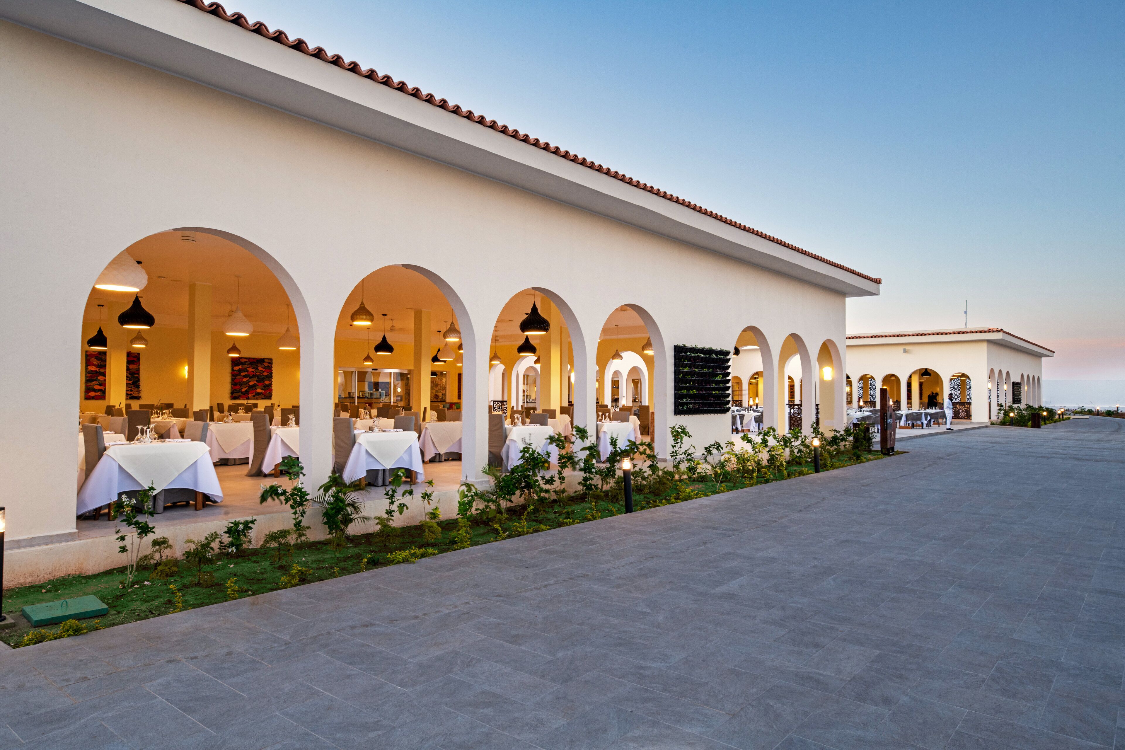 Un restaurante con terraza al aire libre, cubierto por arcos y un patio empedrado.