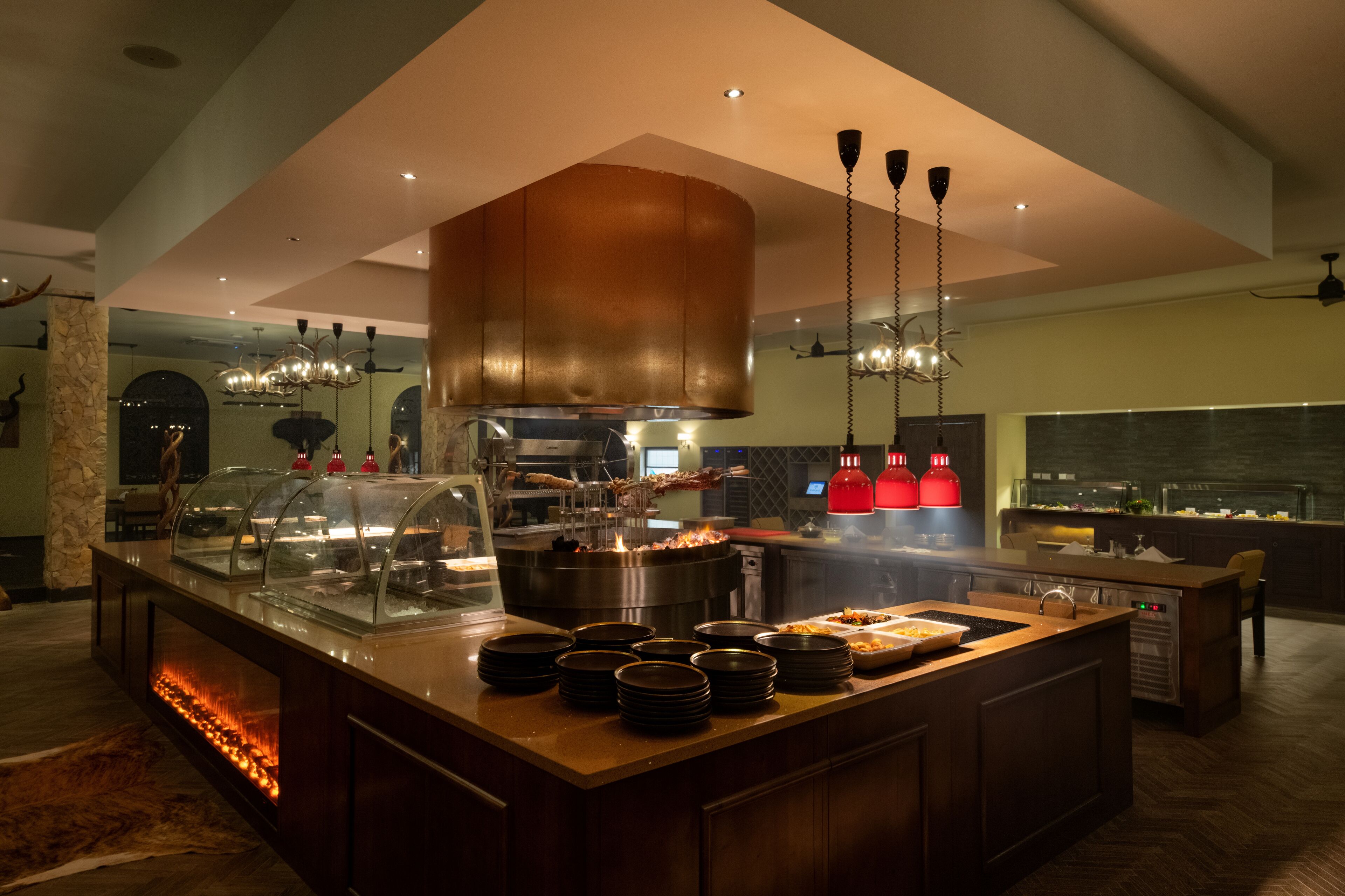 Una cocina moderna con una isla central, campana extractora de cobre y luces colgantes.