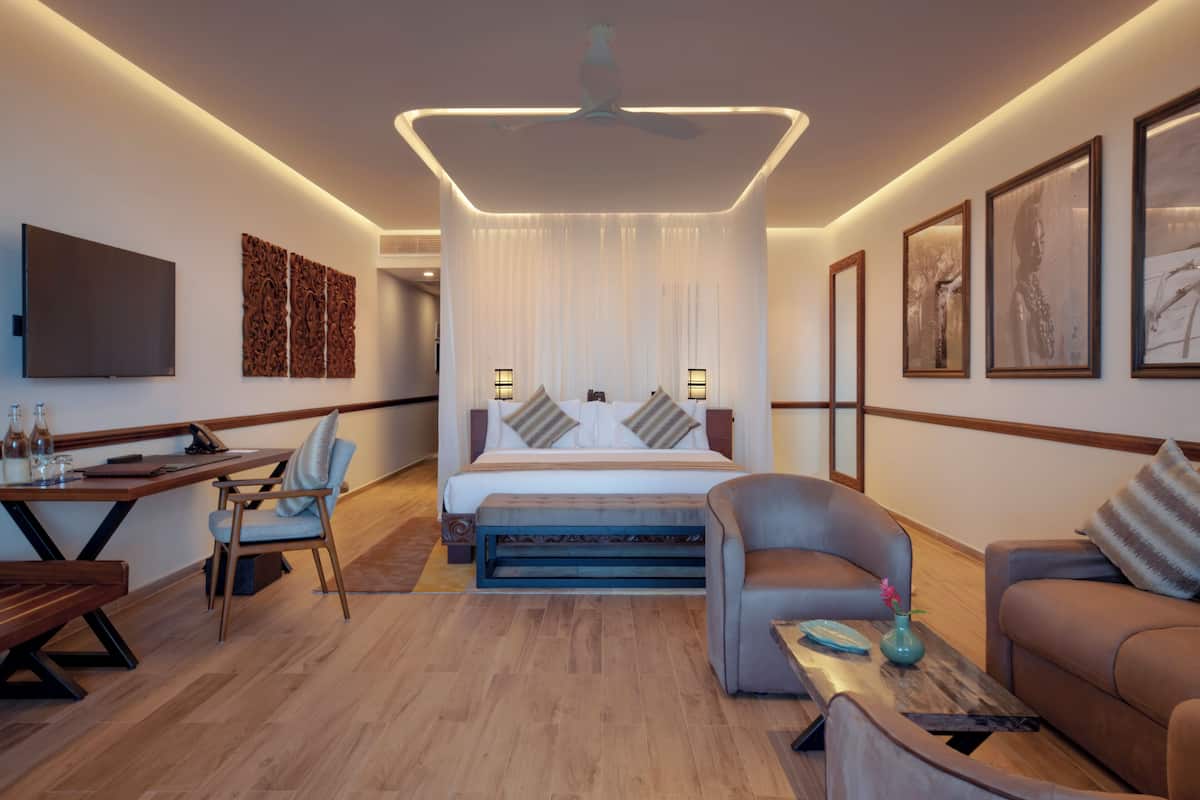 Una habitación de hotel moderna con cama, sofá, escritorio y televisor.