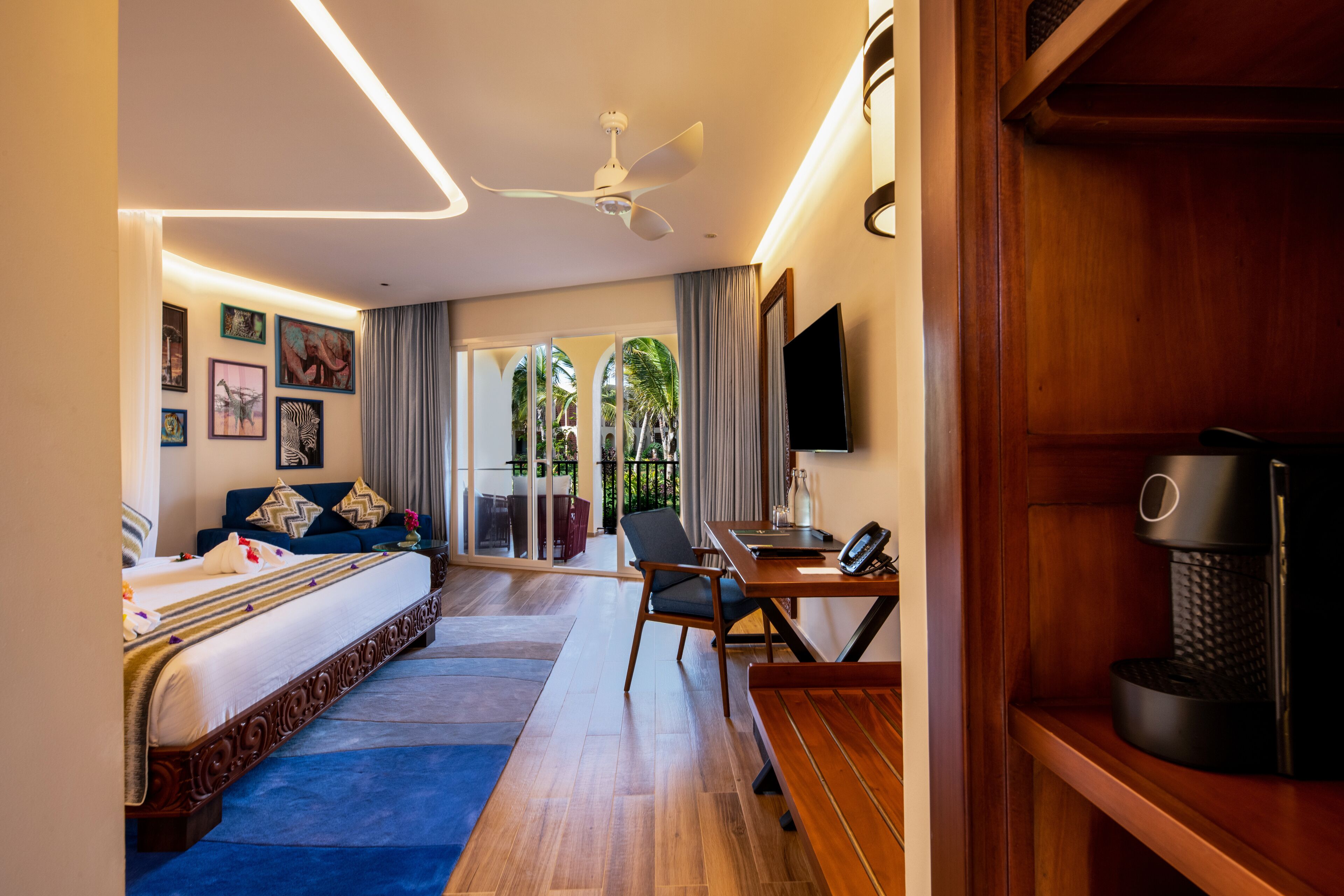A hotel room with a bed, a desk, a chair, a television, and a coffee machine.