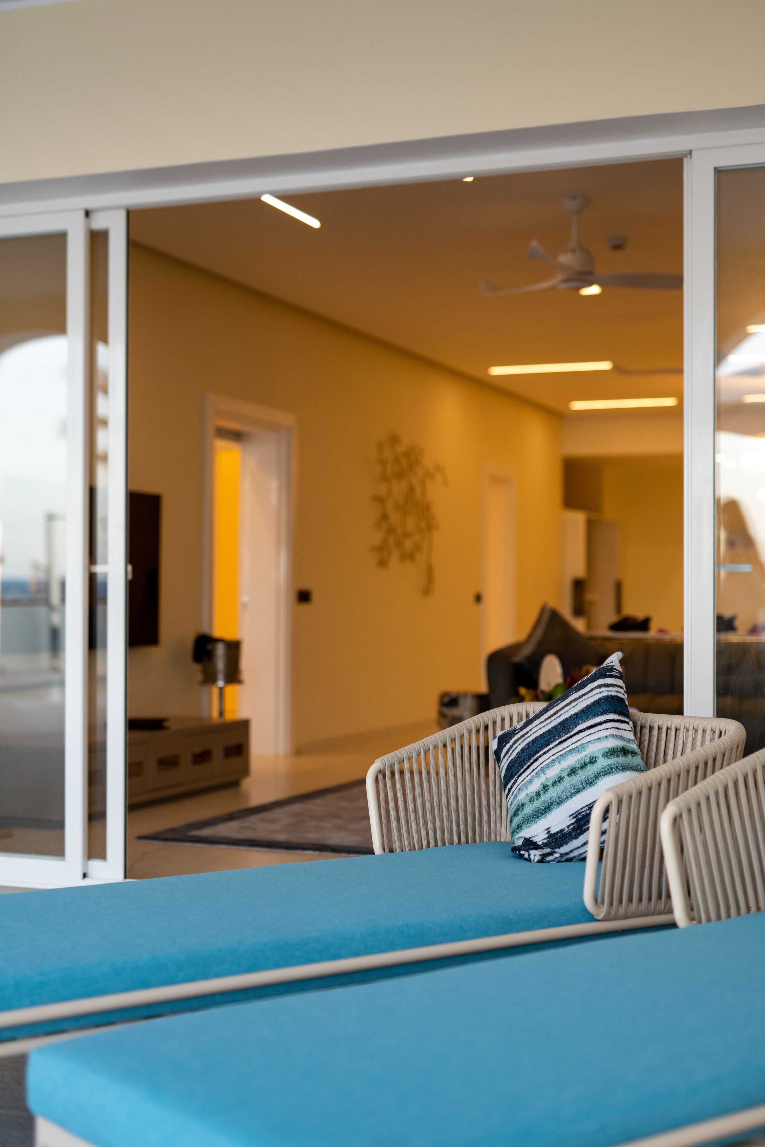 Una sala de estar moderna con un sofá, un ventilador de techo y una puerta que da a otra habitación.