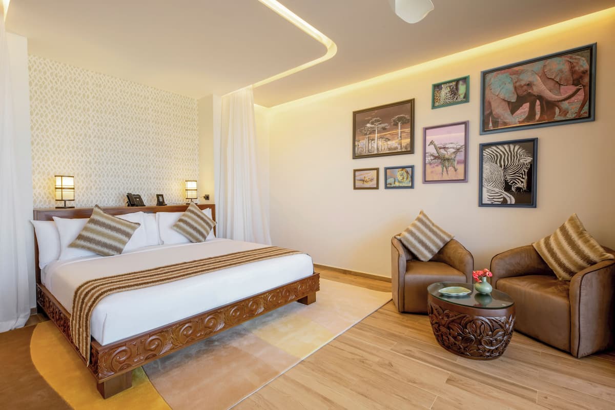 Una habitación de hotel con una cama grande, dos sofás, una mesita de café y decoración en la pared.