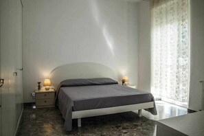 Ein Schlafzimmer mit Bett, Nachttischen und einem Fenster mit Vorhängen.