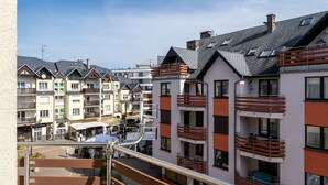 Una hilera de edificios de varios pisos con balcones, un escaparate visible y un cielo despejado.