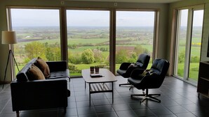 Een ruime woonkamer met een groot raam en uitzicht op een groen landschap.