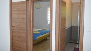A room with a bed, a shower, and a door leading to another room. - Apartment Vapor (Dubrovnik)