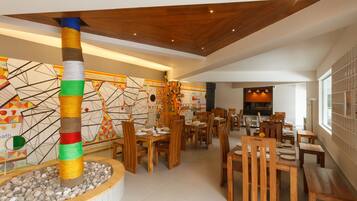 A restaurant with wooden tables and chairs, a decorative pillar, and a geometric wall design.