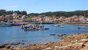 Un pueblo costero con un puerto deportivo, un litoral rocoso y edificios residenciales al fondo.