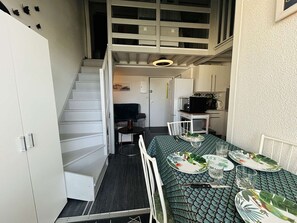A compact living space with a dining area, kitchenette, and a staircase leading to an upper level.