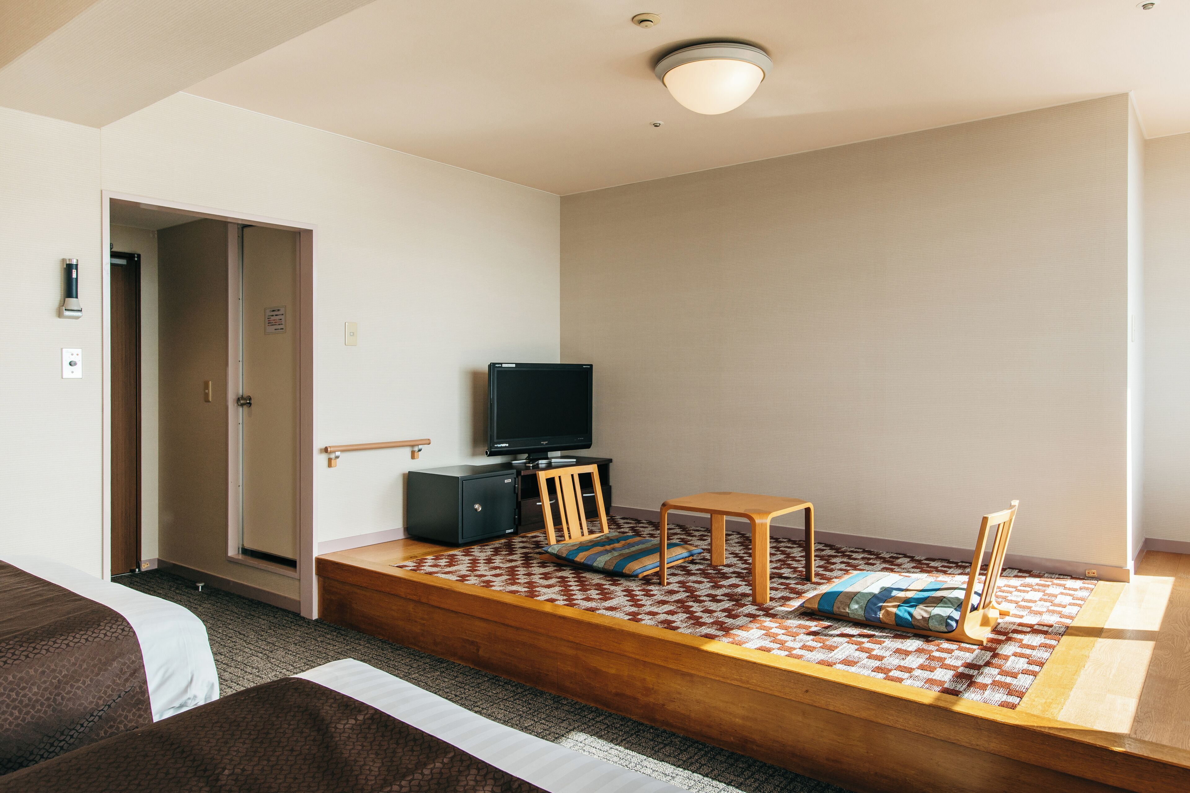 Een hotelkamer met een bed, een televisie, een klein tafeltje en een bank.