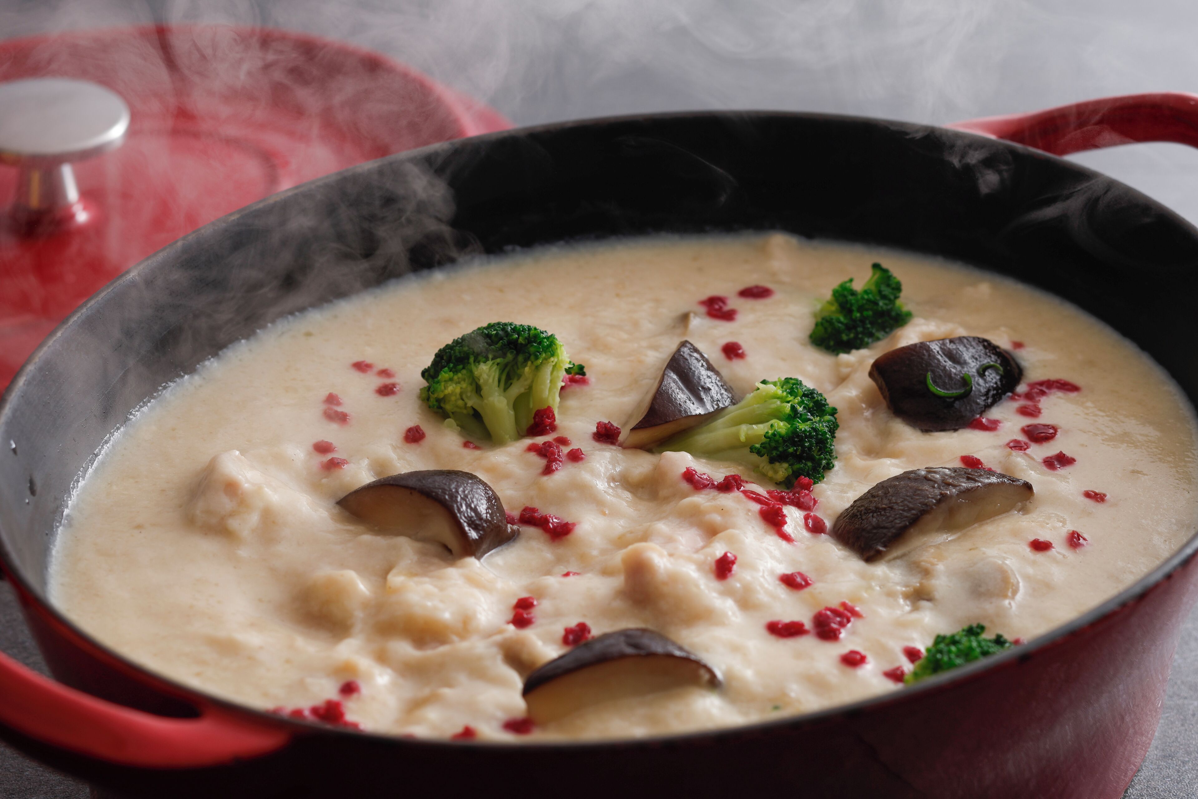 A creamy soup with broccoli and mushrooms in a red pot.