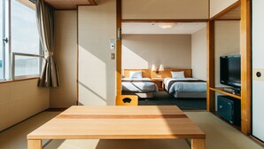 Une chambre d’hôtel avec une table en bois, deux lits, un téléviseur et une vue sur l’extérieur.